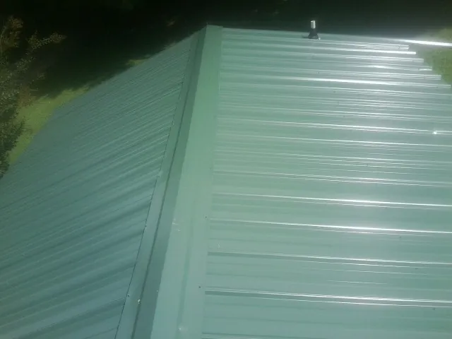 New green metal panels meeting at the ridge of a roof — Flat Roof Repair work by our crew in Ridge