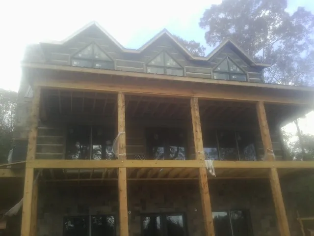 Dormers and porch framing on a large log home under construction — Roof Coating work by our crew in Ridge