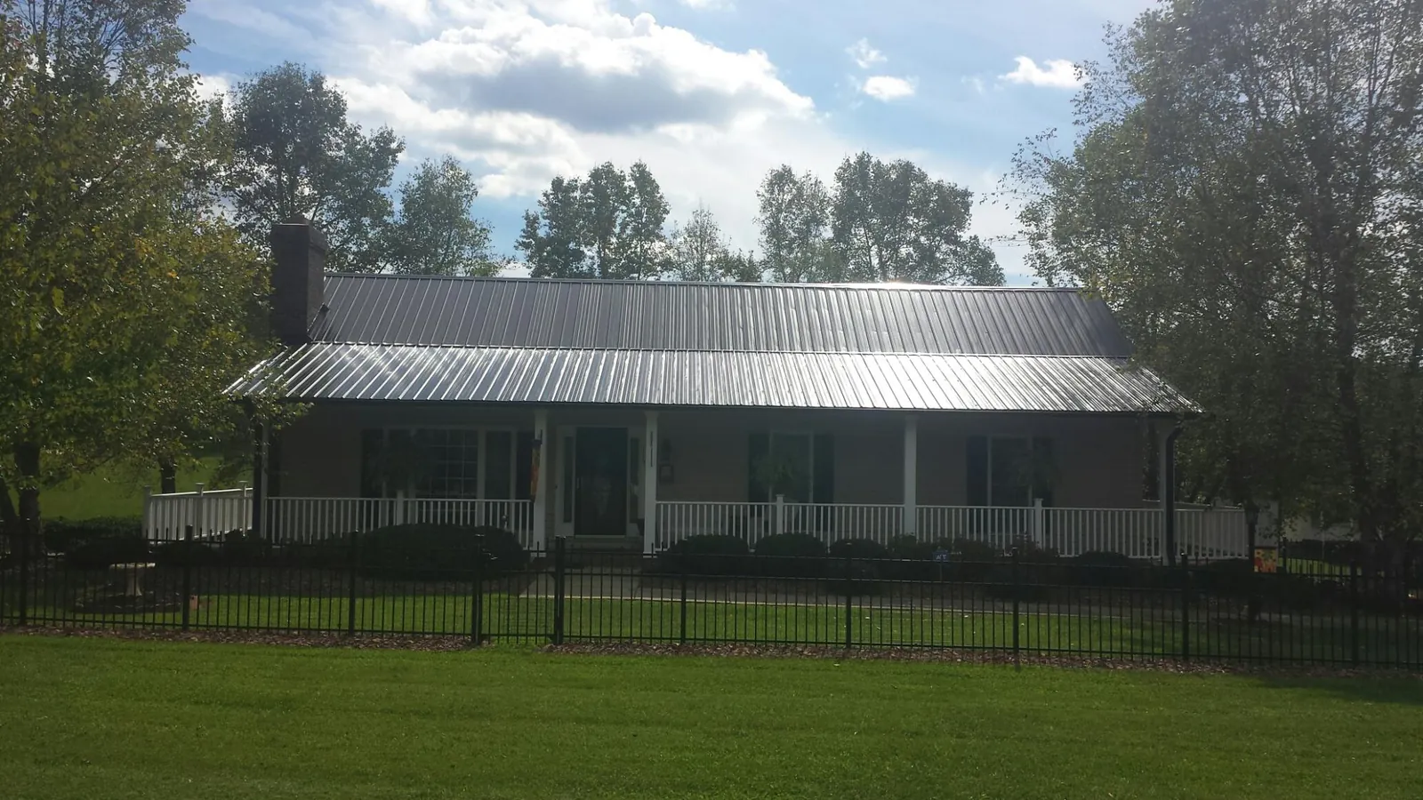Gray metal roof on a brick ranch with a full width front porch — Gutter Guard Installation work by our crew in Ridge