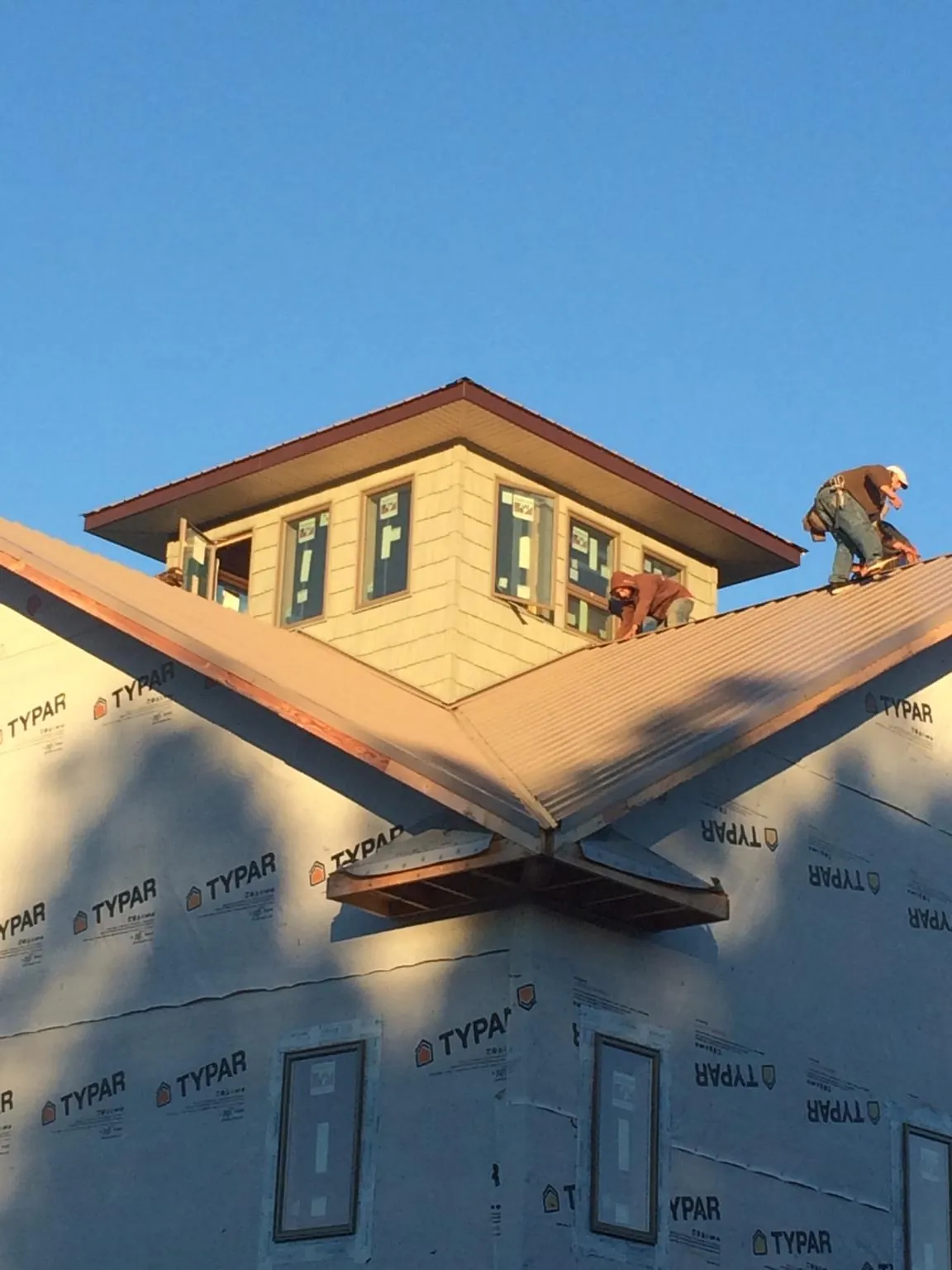 Roofers working around a rooftop cupola on a new metal roof at sunset — Roof Waterproofing in Ridge by Roofing Brothers